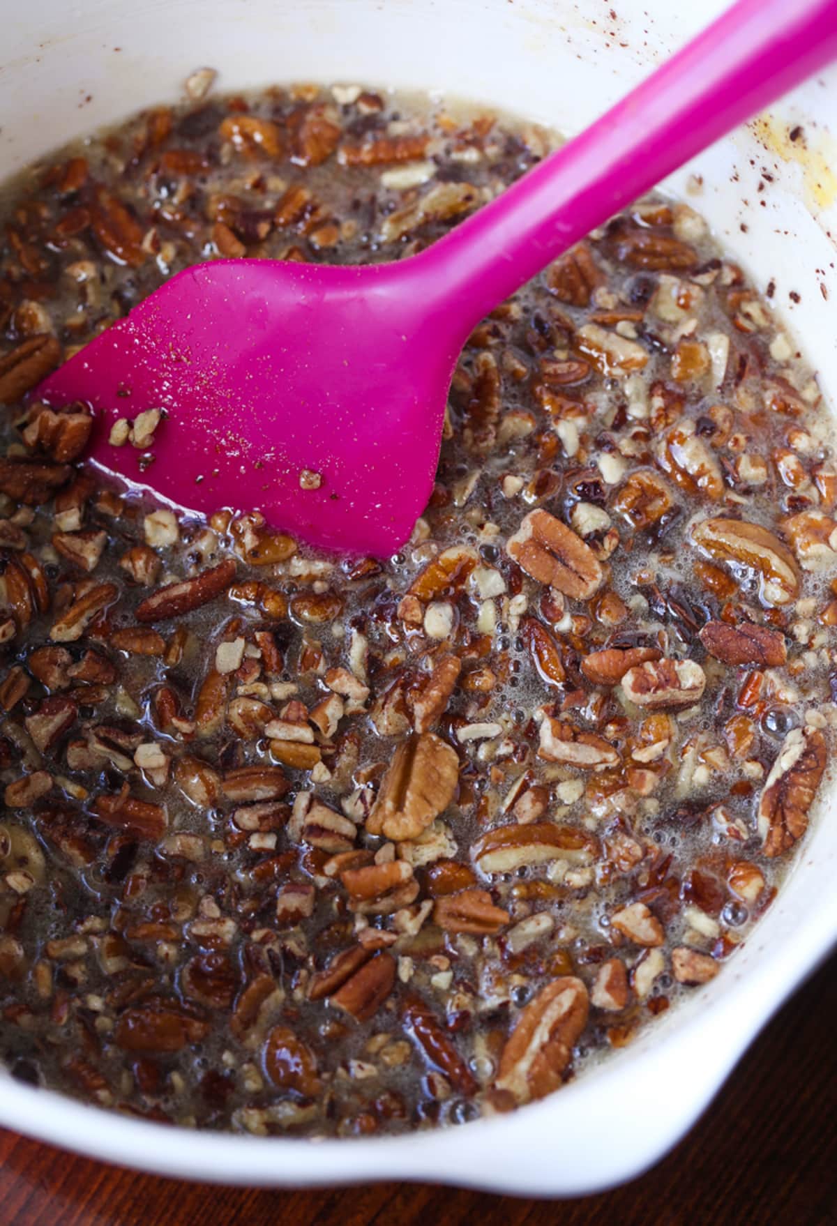 Chocolate Pecan Pie filling in a mixing bowl with a pink rubber spatula