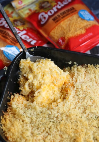 A serving spoon removing a corner piece from a casserole dish.