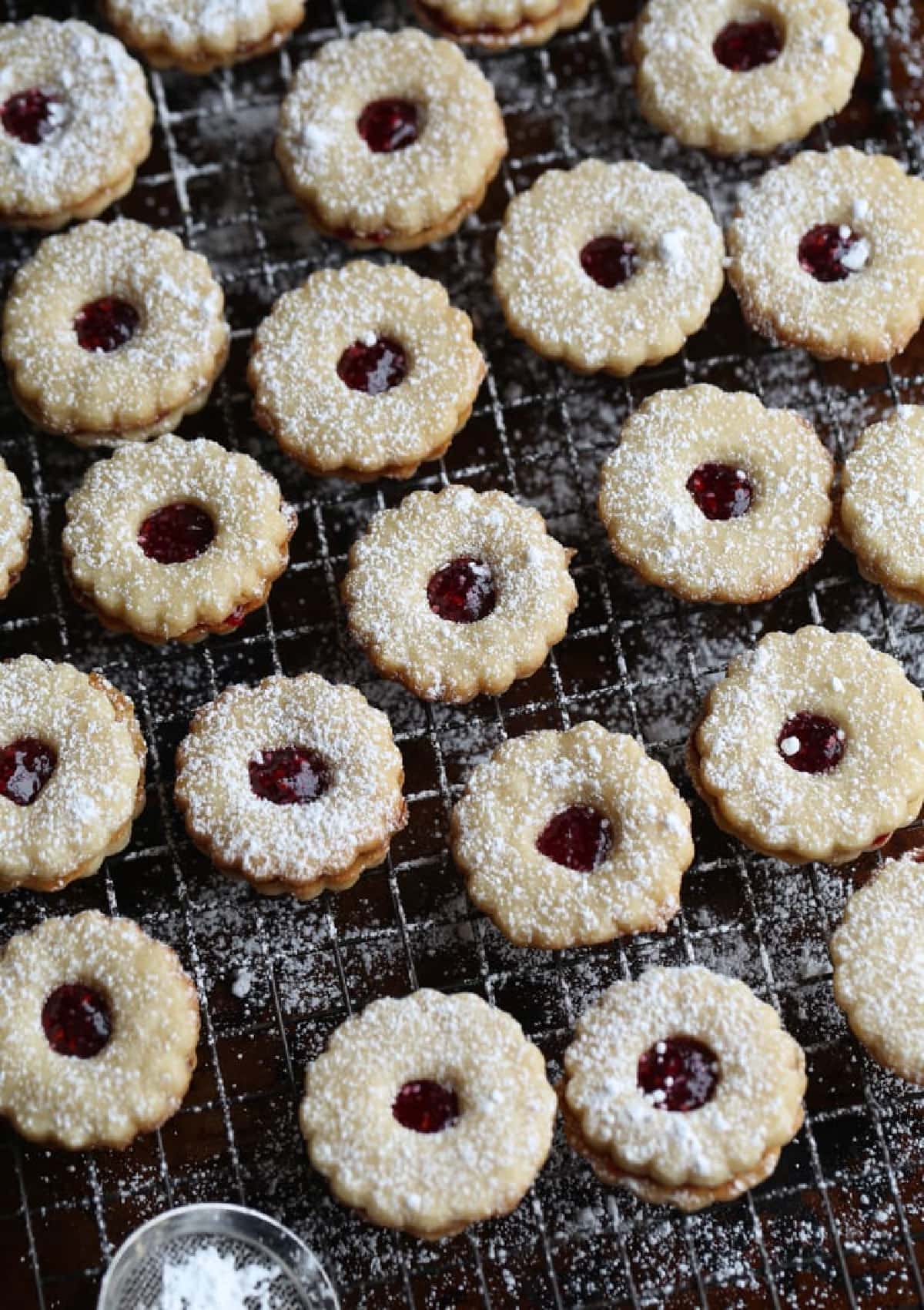 Linzer Cookies on a wire rack dusted with powdered sugar