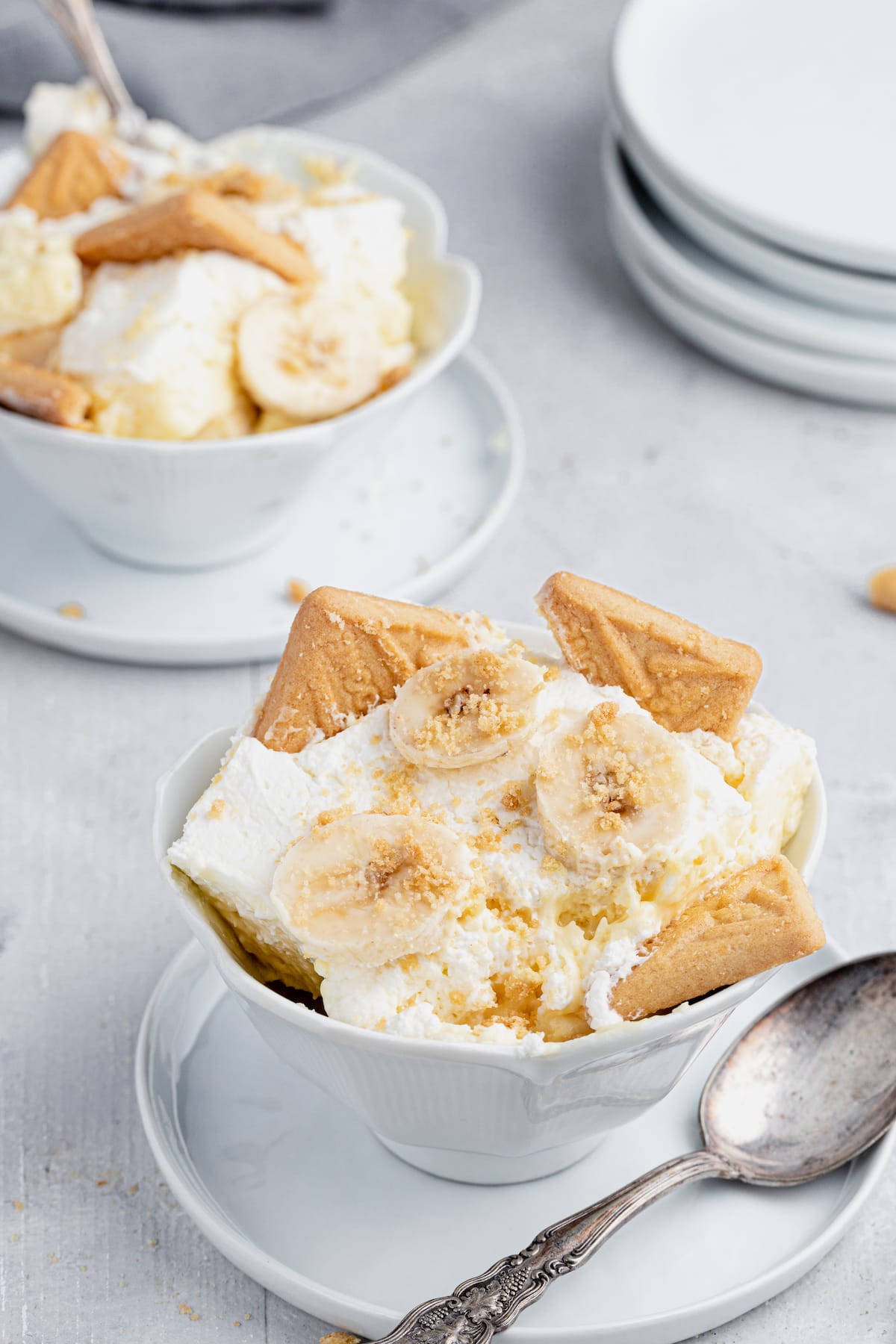 This is the BEST homemade banana pudding recipe! Layers of ripe bananas, cookies, and fluffy pudding make this a favorite no-bake dessert. Two bowls of banana pudding.