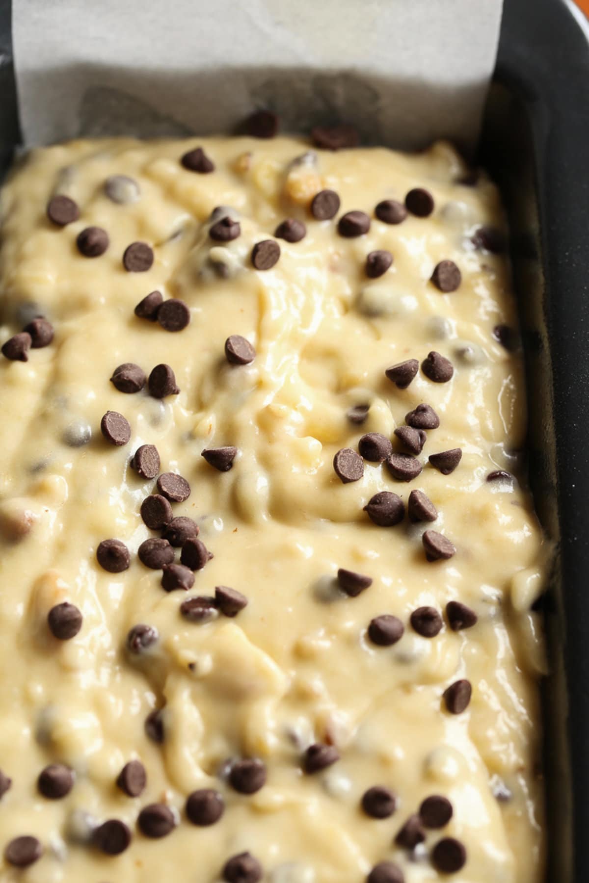 Banana bread batter in a loaf pan topped with mini chocolate chips before going in the oven.