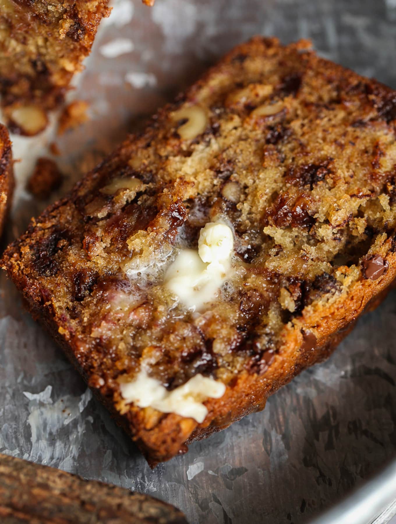 A slice of chocolate chip banana bread topped with melted butter.