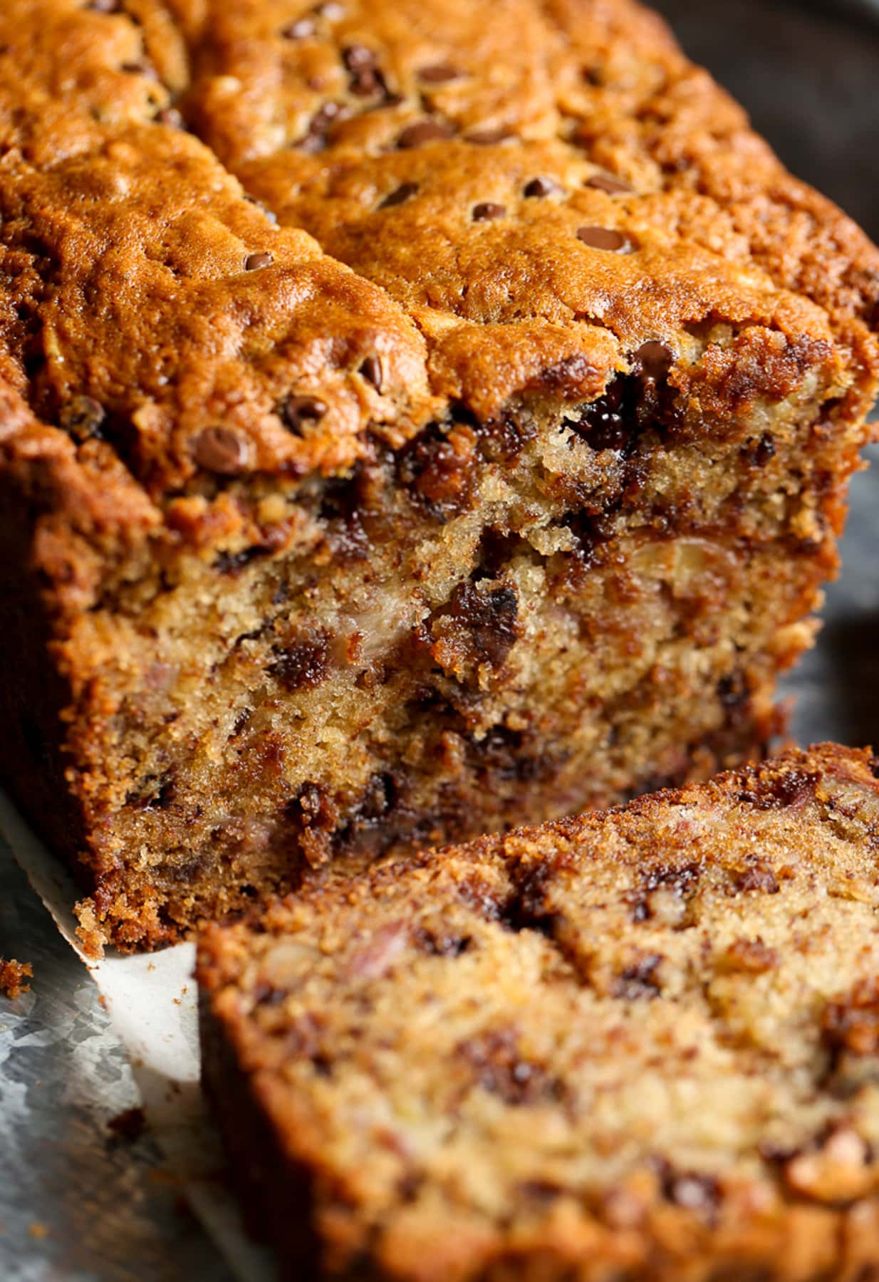 A loaf of chocolate chip banana bread with one slice cut.