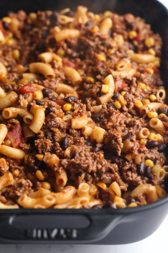Chili mac ingredients combined in a large black casserole dish.