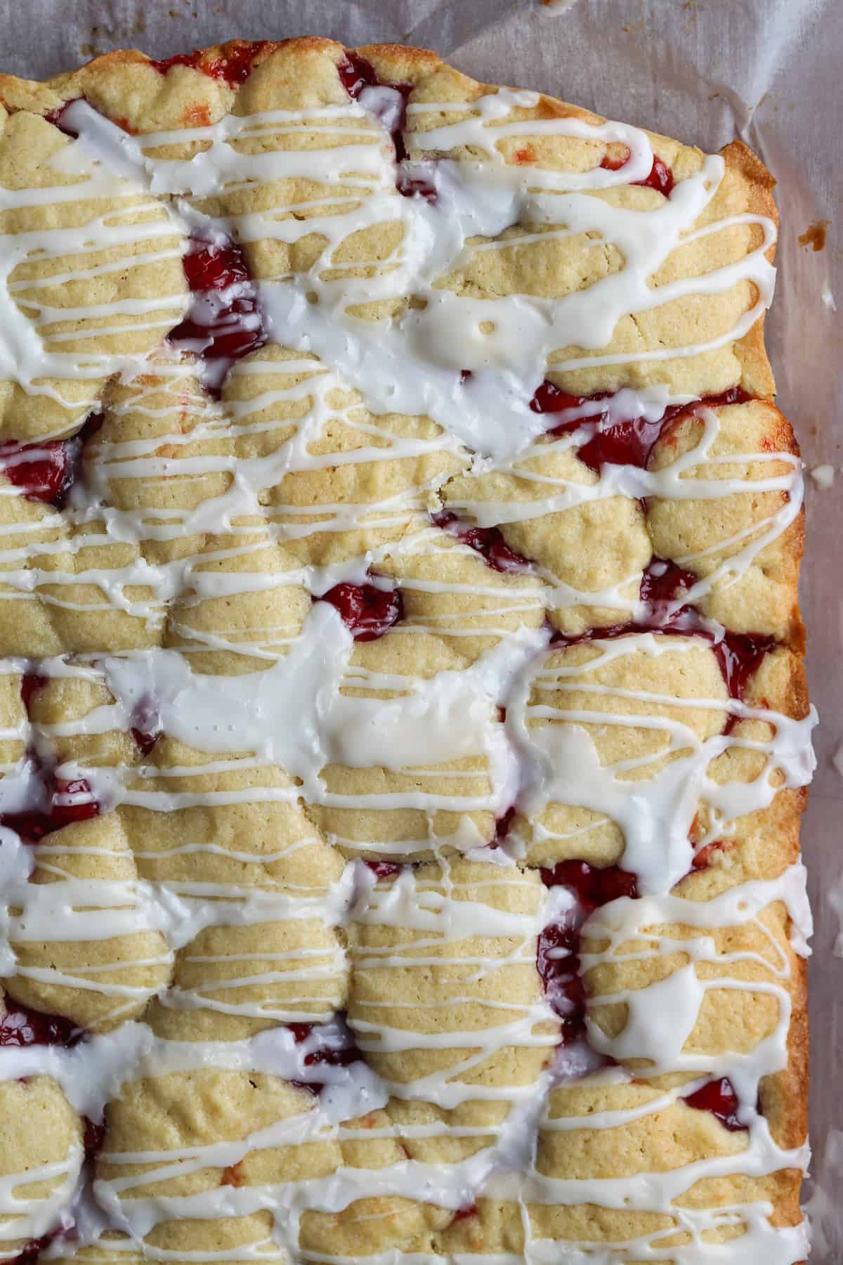 Cherry cake baked in a 9x13 pan with white icing drizzled on top.