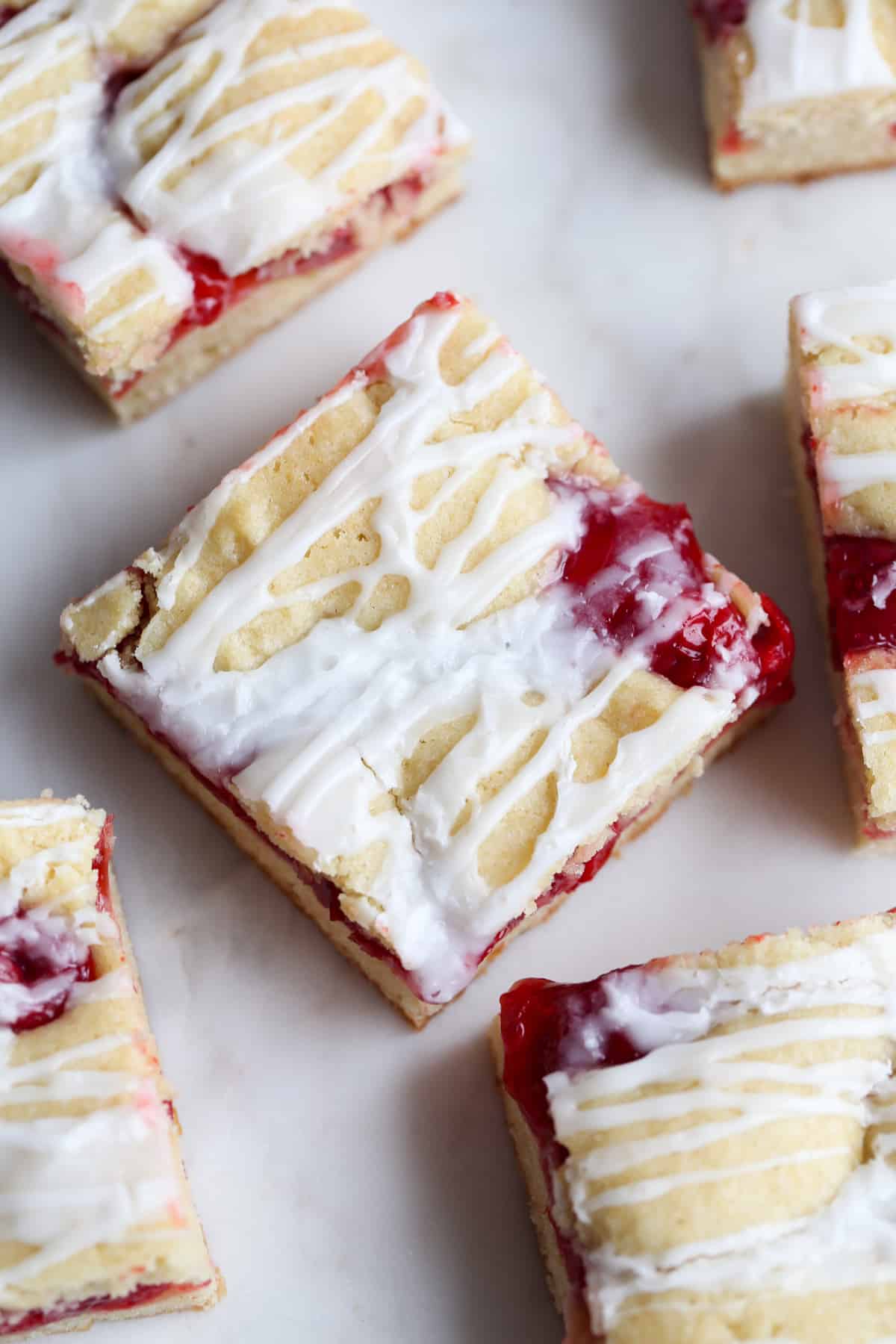Slices of Cobblestone Cherry Cake cut into squares with white icing drizzled on top from above on a white tray.