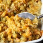 A spoon scoops Chicken Cordon Bleu Casserole from a baking dish.