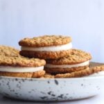 Oatmeal cream pies stacked in a stoneware bowl.