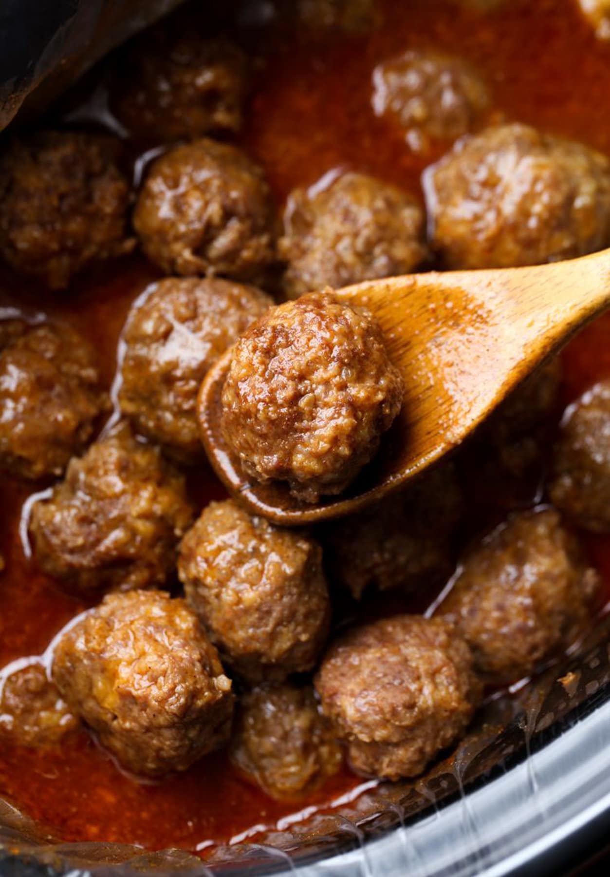 Cheesy Meatballs being prepared with a wooden spoon. 