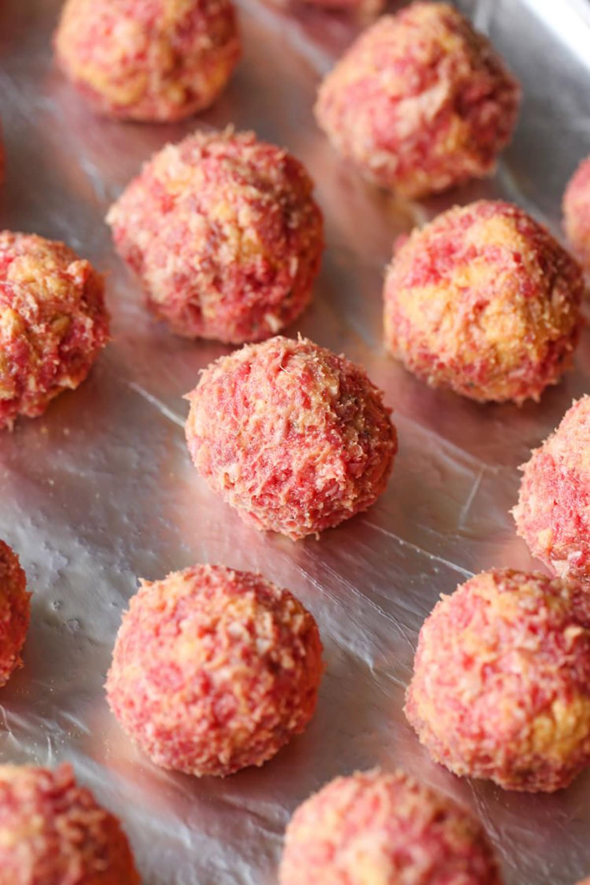 Raw meatballs displayed on a pan.