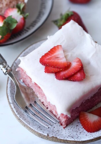 a piece of strawberry cake on a plate from above with fresh strawberry slices