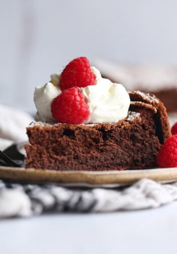 Flourless Chocolate Cake topped with whipped cream and raspberries