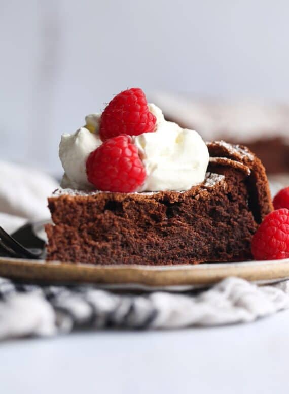 Flourless Chocolate Cake topped with whipped cream and raspberries
