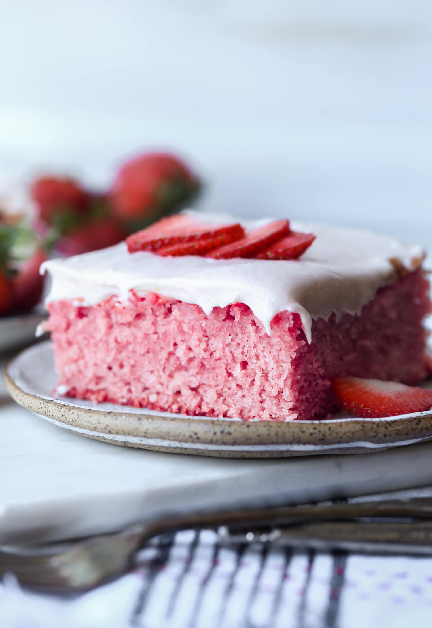 a slice of strawberry shortcake on a plate topped with fresh strawberry slices