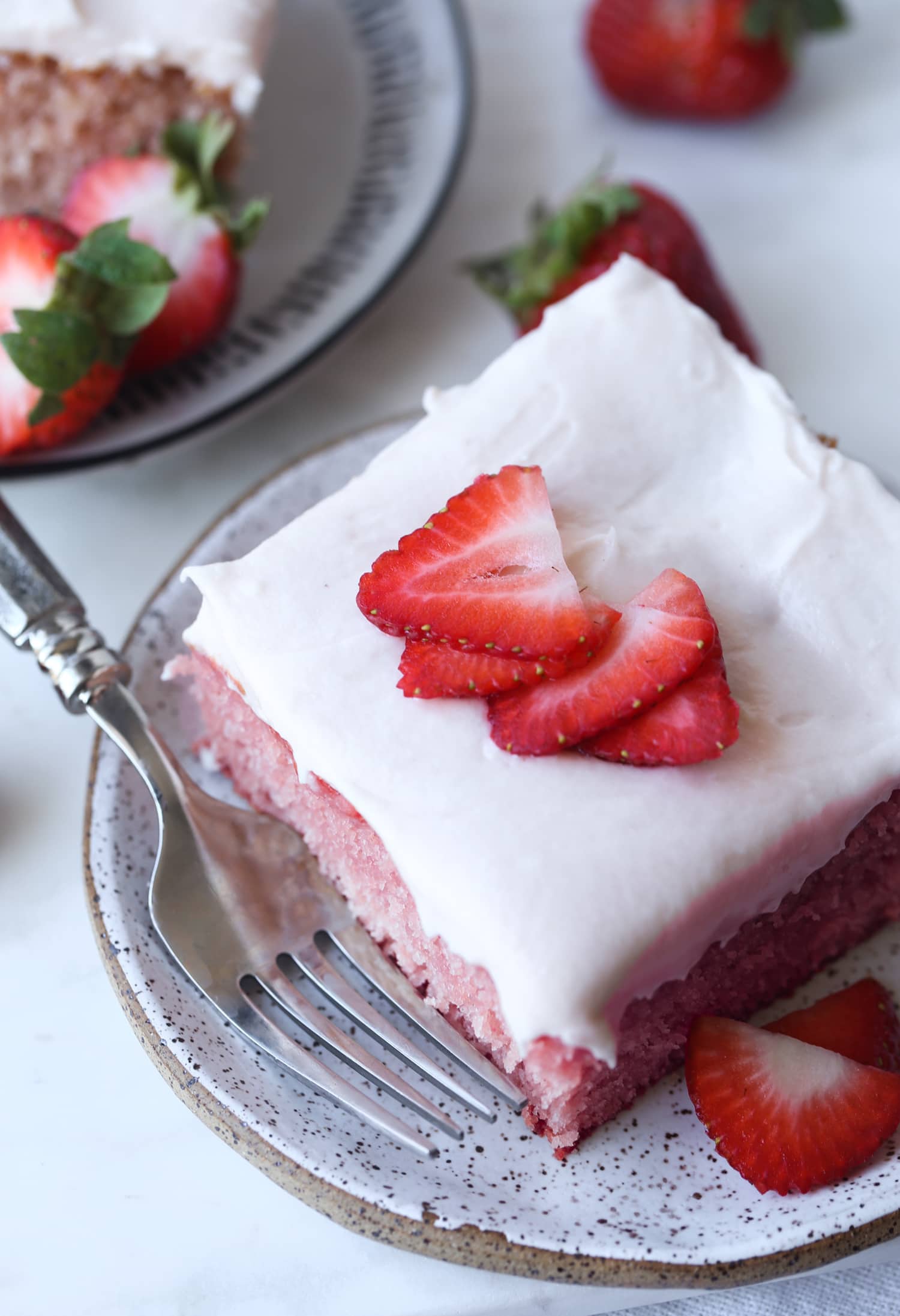 a piece of strawberry cake on a plate from above with fresh strawberry slices