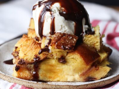 Bread pudding plated and then toped with vanilla ice cream and chocolate syrup
