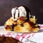 Bread pudding plated and then toped with vanilla ice cream and chocolate syrup