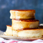 stacked Japanese pancakes on a plate with maple syrup dripping down the sides