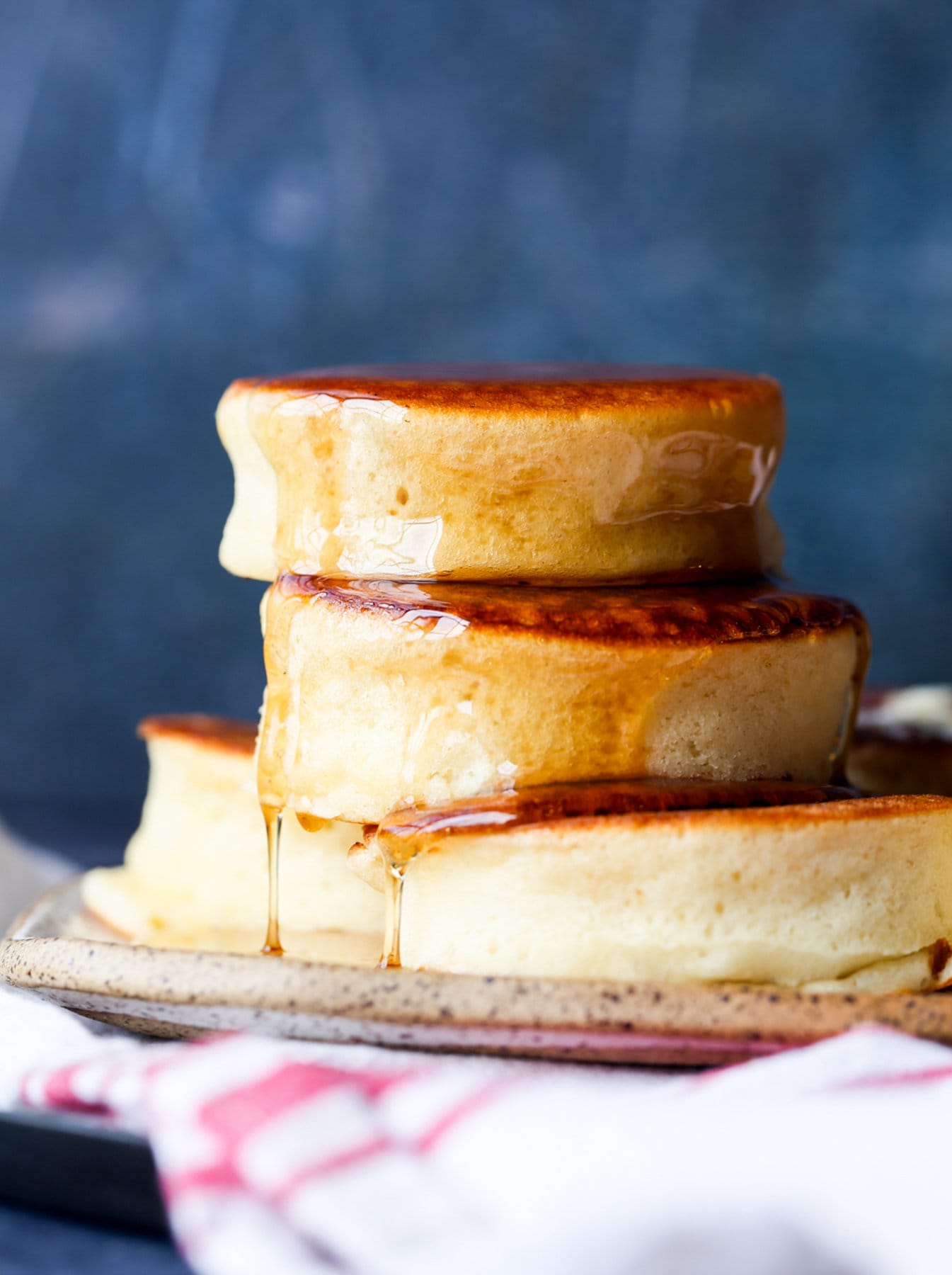 stacked Japanese pancakes on a plate with maple syrup dripping down the sides