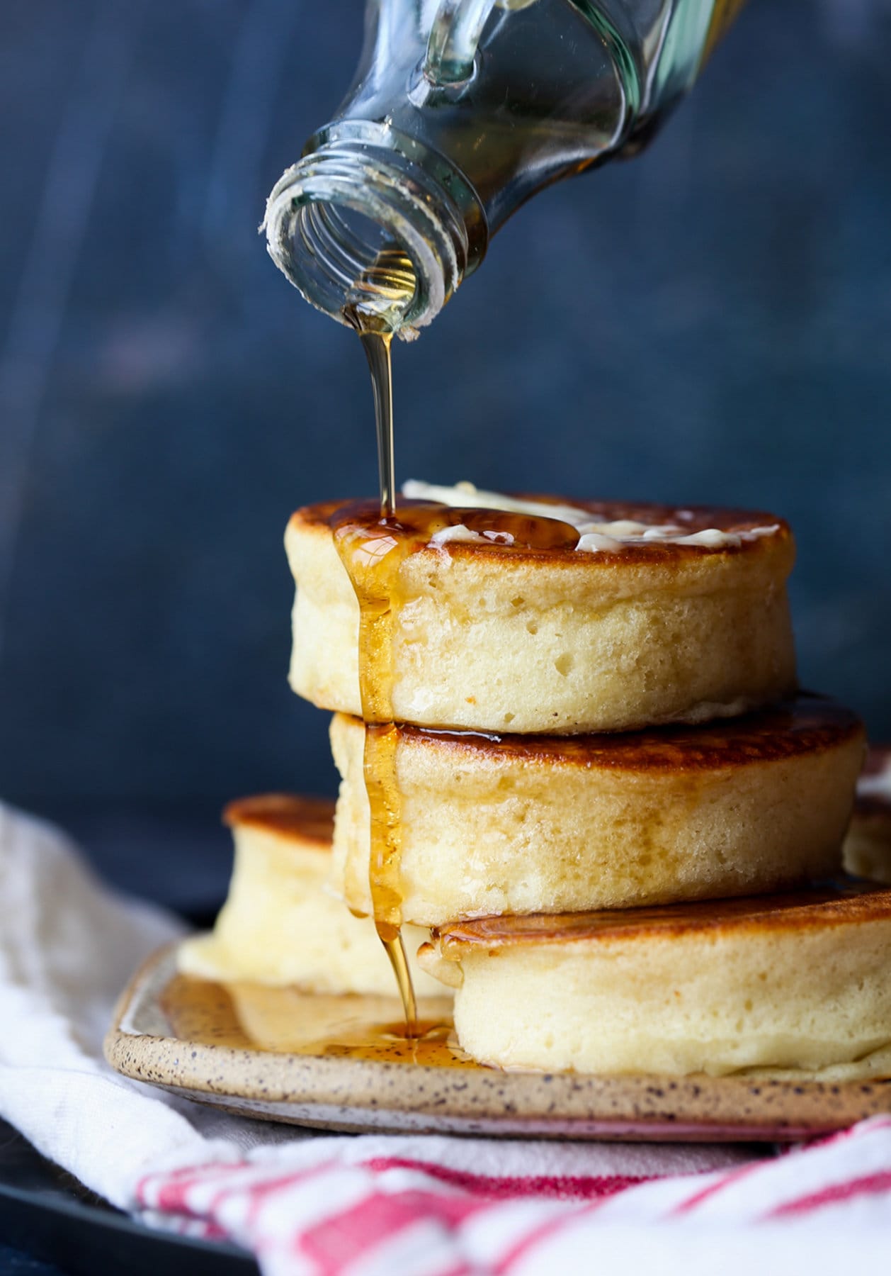 pouring maple syrup on top of stacked Japanese pancakes
