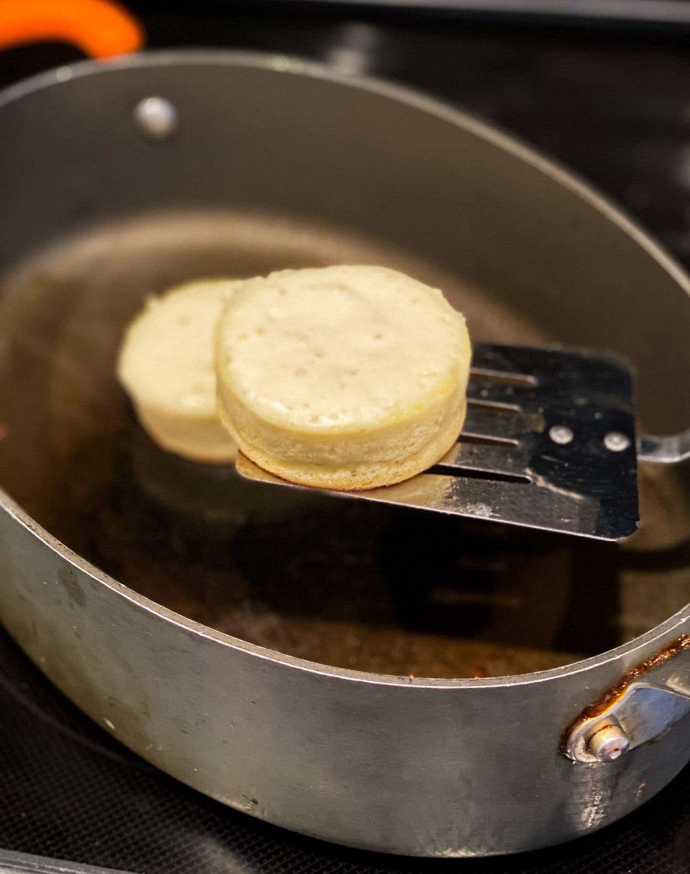 Flipping a soufflé pancake in a nonstick skillet with a spatula