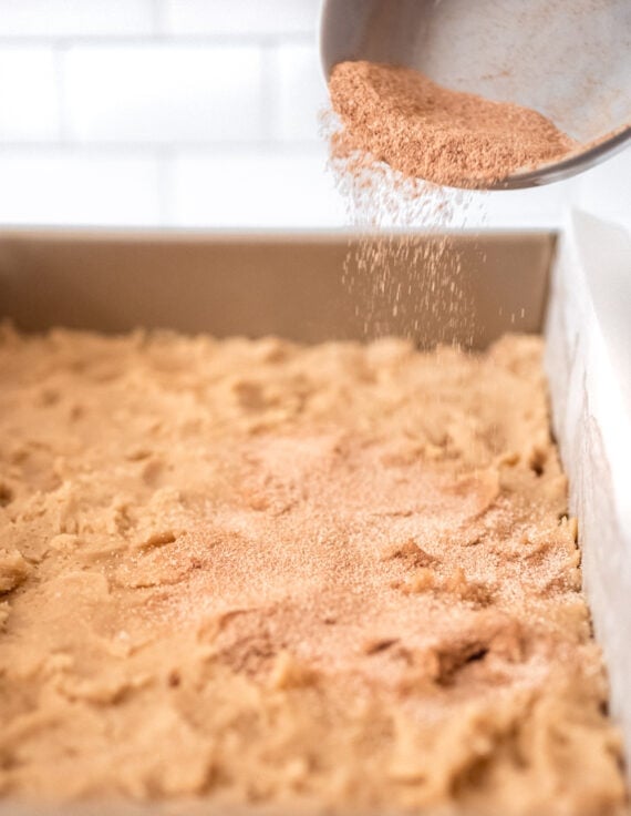 Sprinkling cinnamon sugar on cookie bars