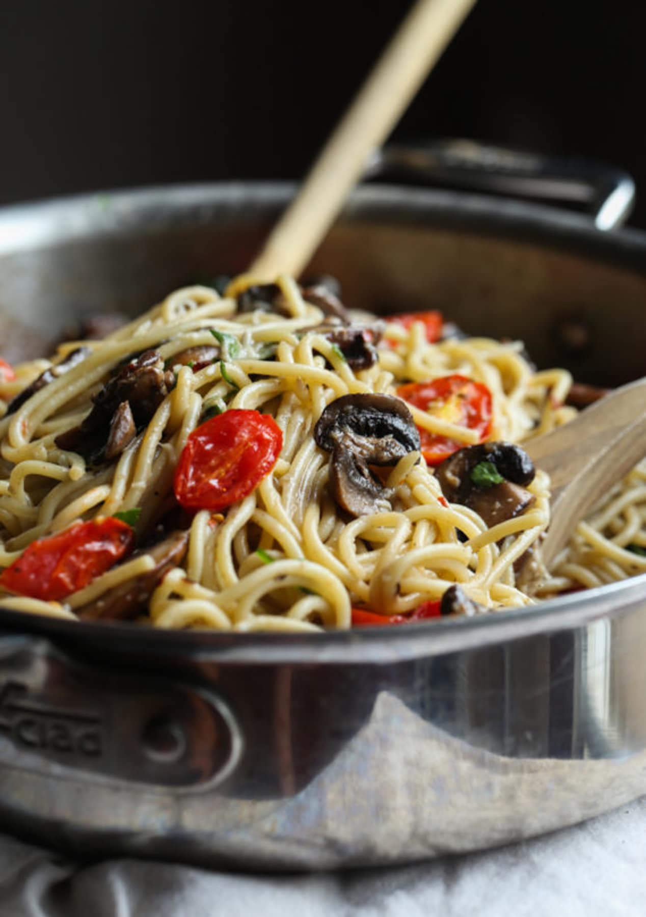 Pasta with garlic butter and roasted tomatoes and mushrooms in a stainless steel skillet