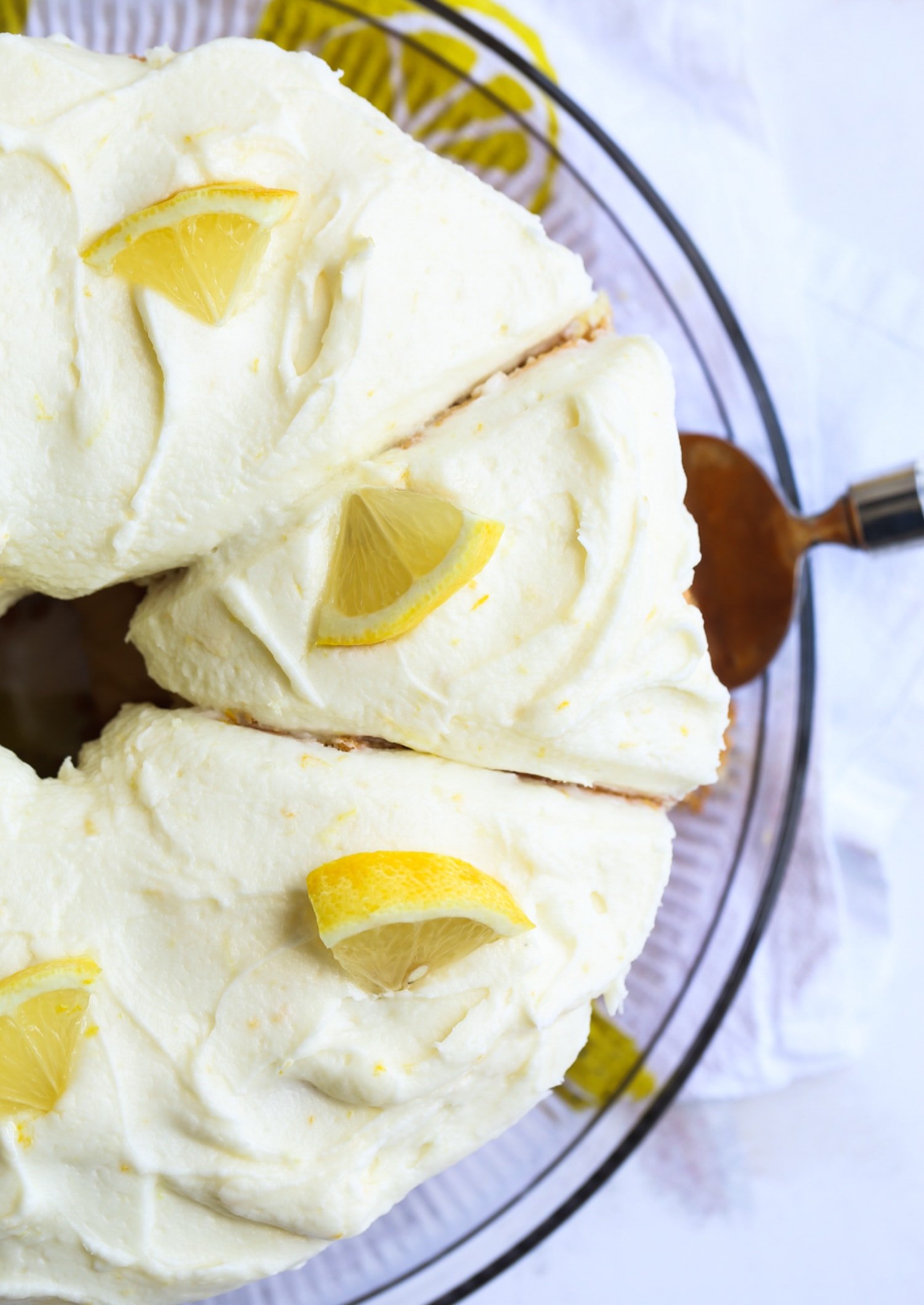 sliced lemon chiffon cake from above with lemon frosting and fresh lemon pieces