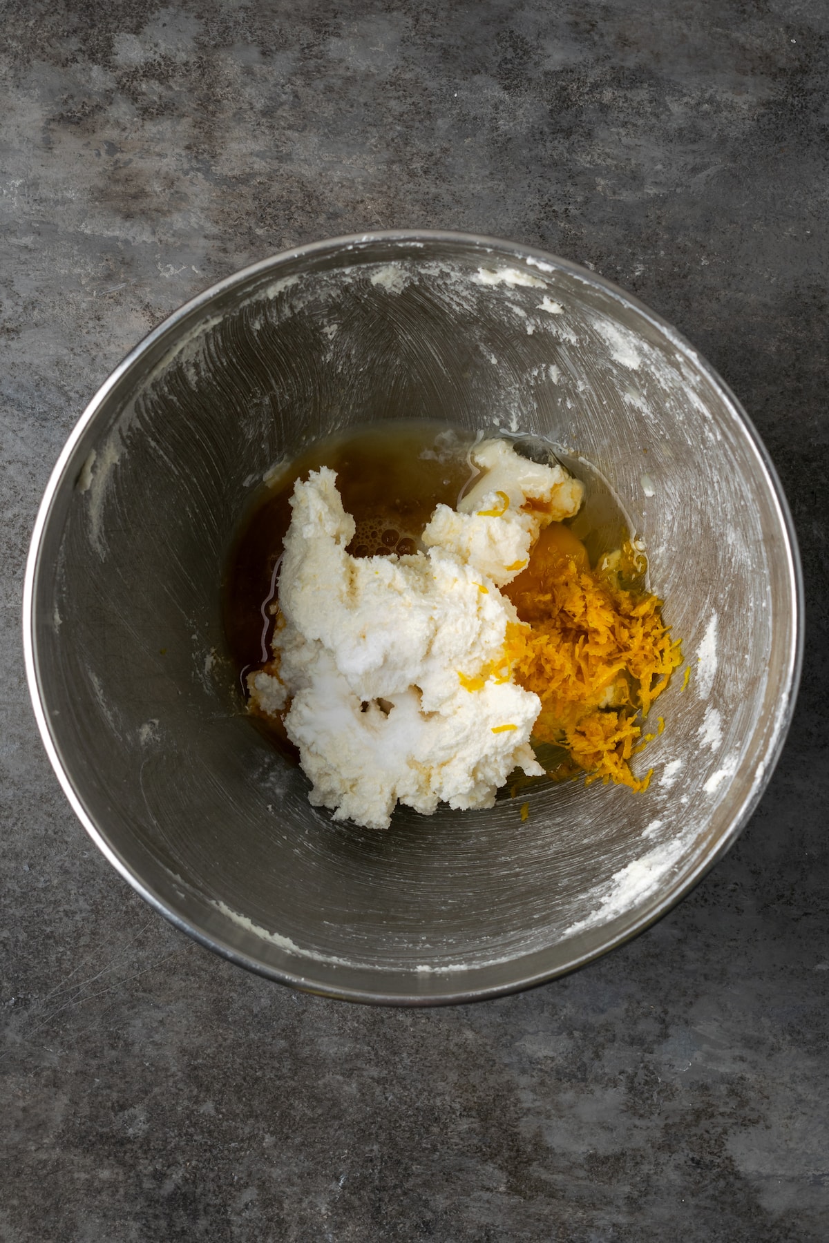 Orange crinkle cookie dough ingredients combined in a metal mixing bowl.