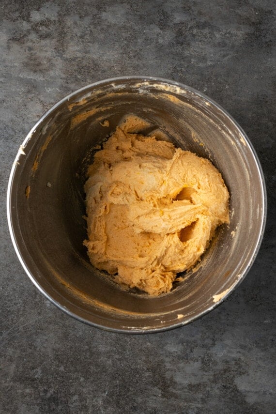 Orange crinkle cookie dough in a metal mixing bowl.