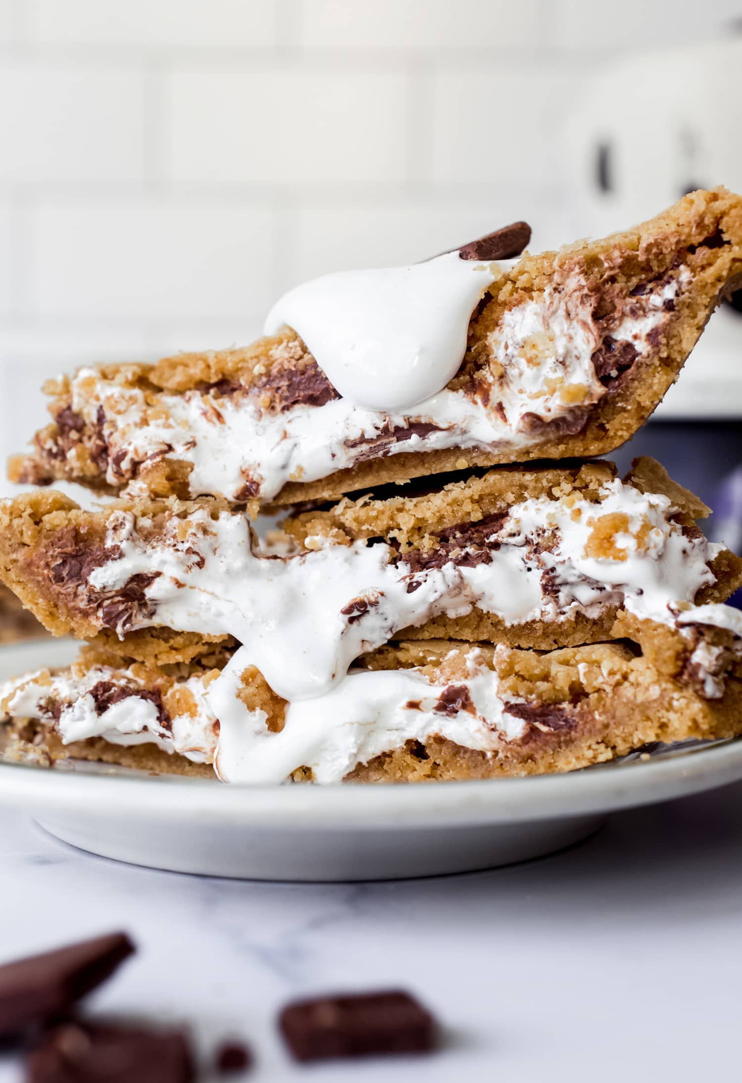 Auf einem Teller gestapelte S'mores-Kuchenstücke, aus denen Marshmallow-Creme herausquillt