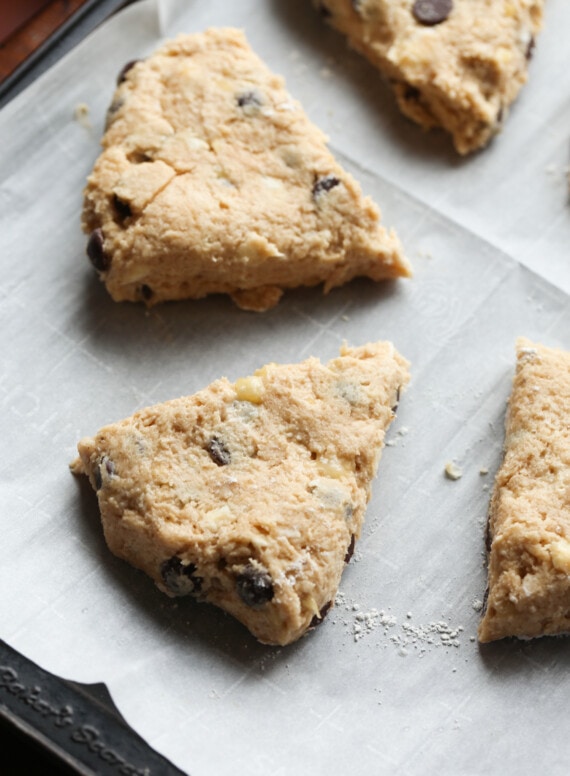 Scone dough cut into a triangle on a parchment lined baking sheet