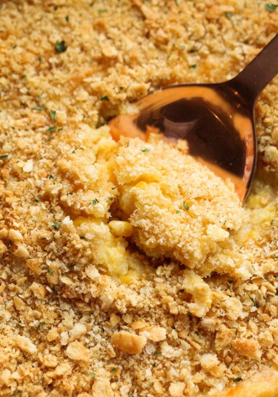 A wooden spoon scooping creamed corn casserole