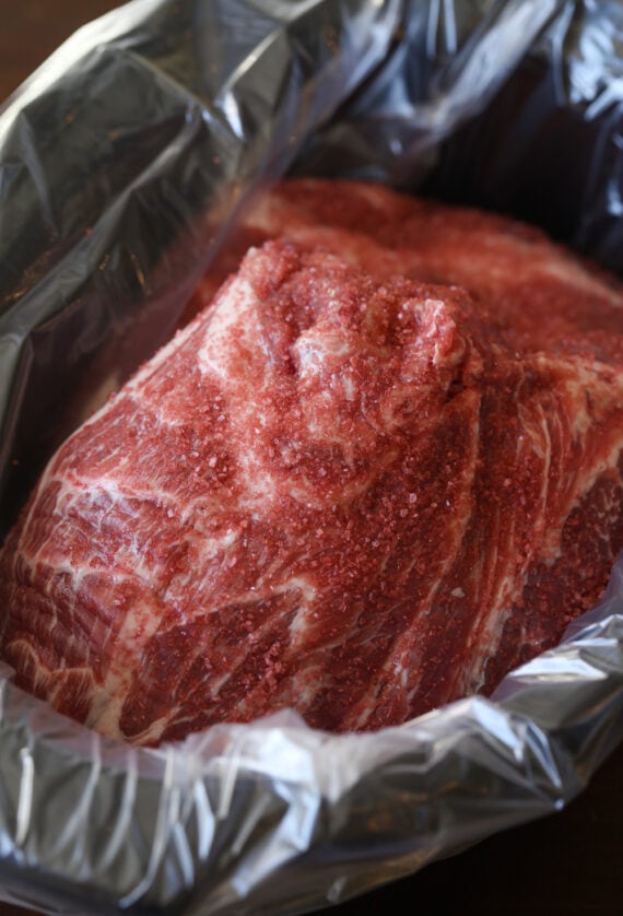 A boneless pork butt roast in a lined crock pot.