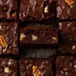 Close up overhead view of bourbon pecan brownies, with one brownie propped up on its side to show the texture inside.