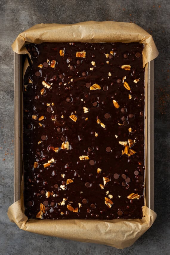 Bourbon pecan brownie batter in a lined baking pan.