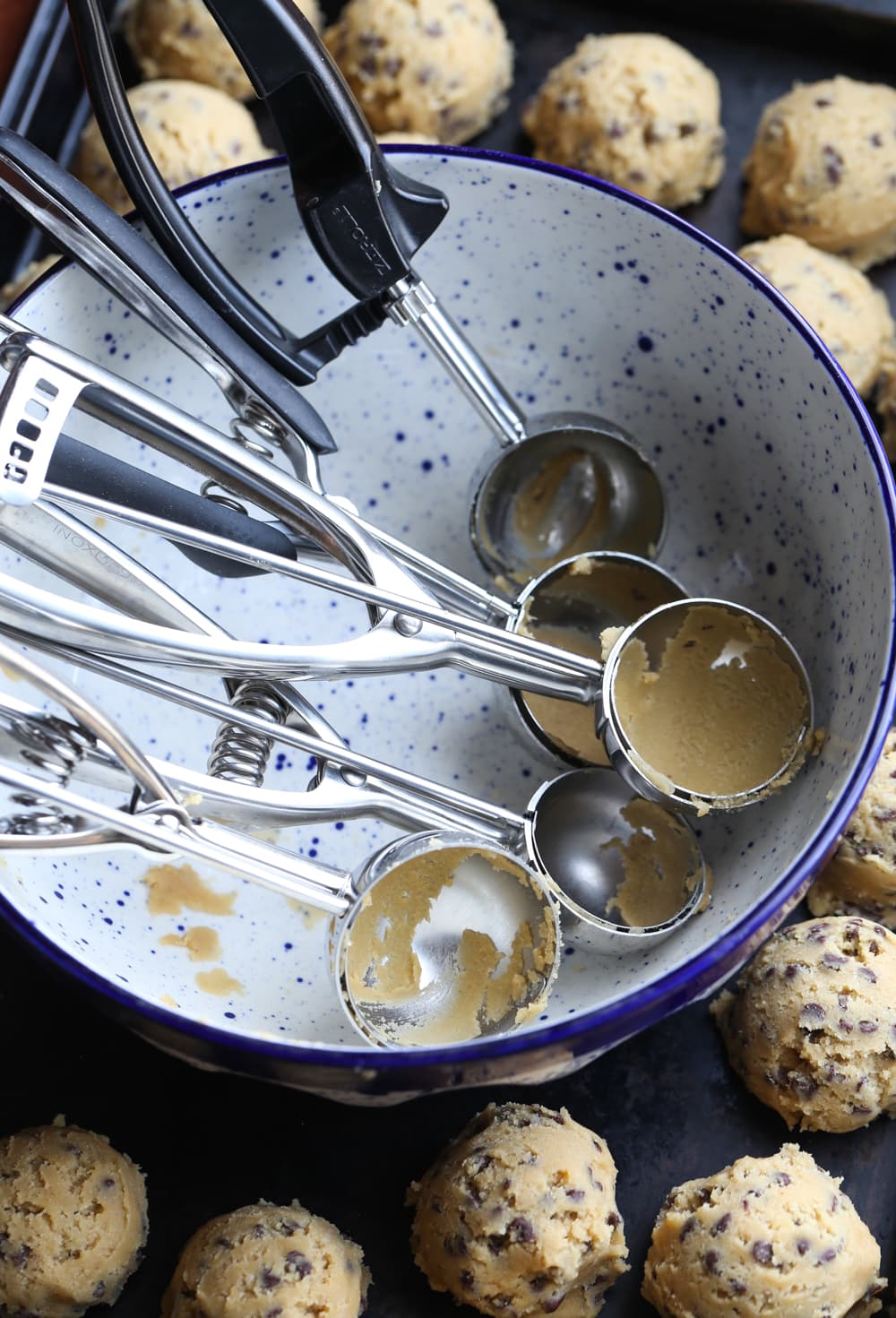 Cookie Scoops in a Bowl Surrounded by Cookie Dough Balls