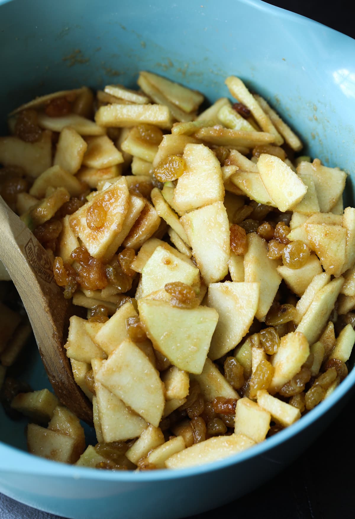 A blue bowl filled with chopped sliced apples coated in cinnamon sugar