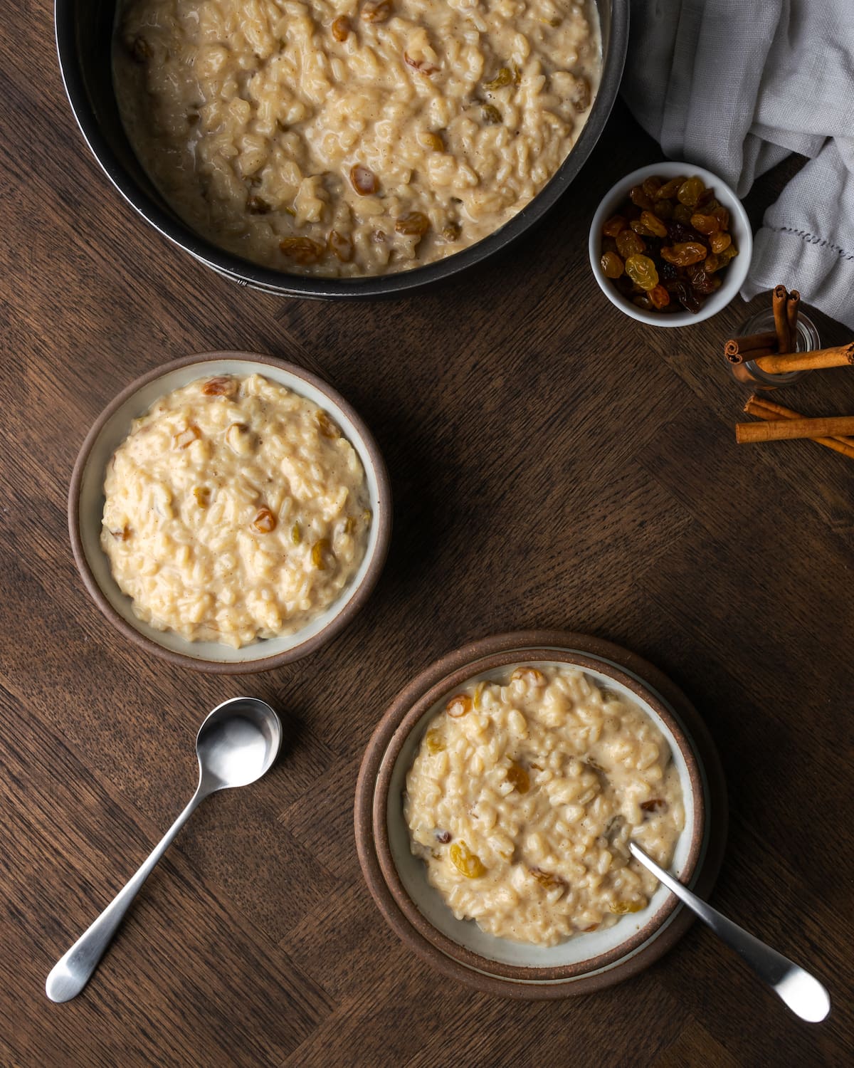 Two small bowls of rice pudding next to a full saucepan.