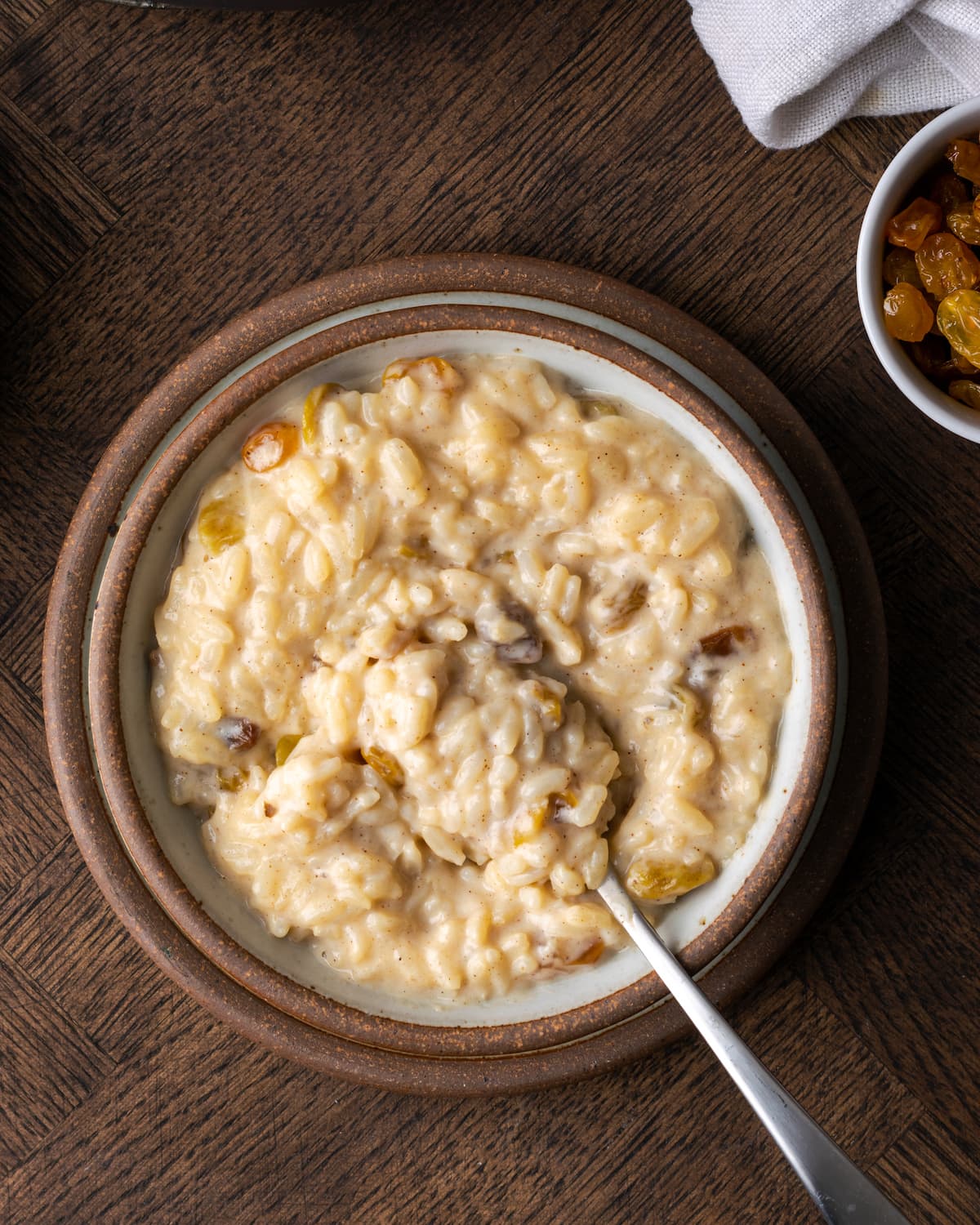 Top view of a bowl of creamy rice pudding with a spoon.