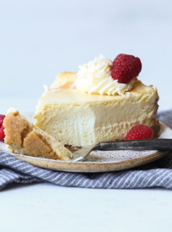 Slice of cheesecake on a plate with a bite taken out