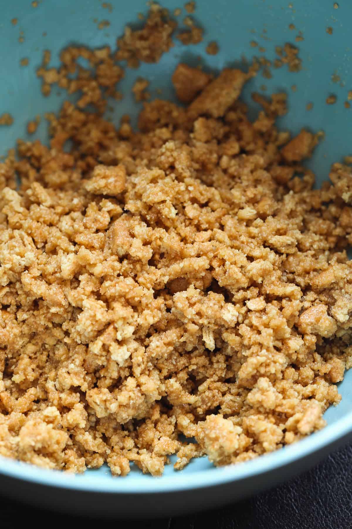 Graham Cracker crumbs mixed with butter and sugar in a blue mixing bowl.