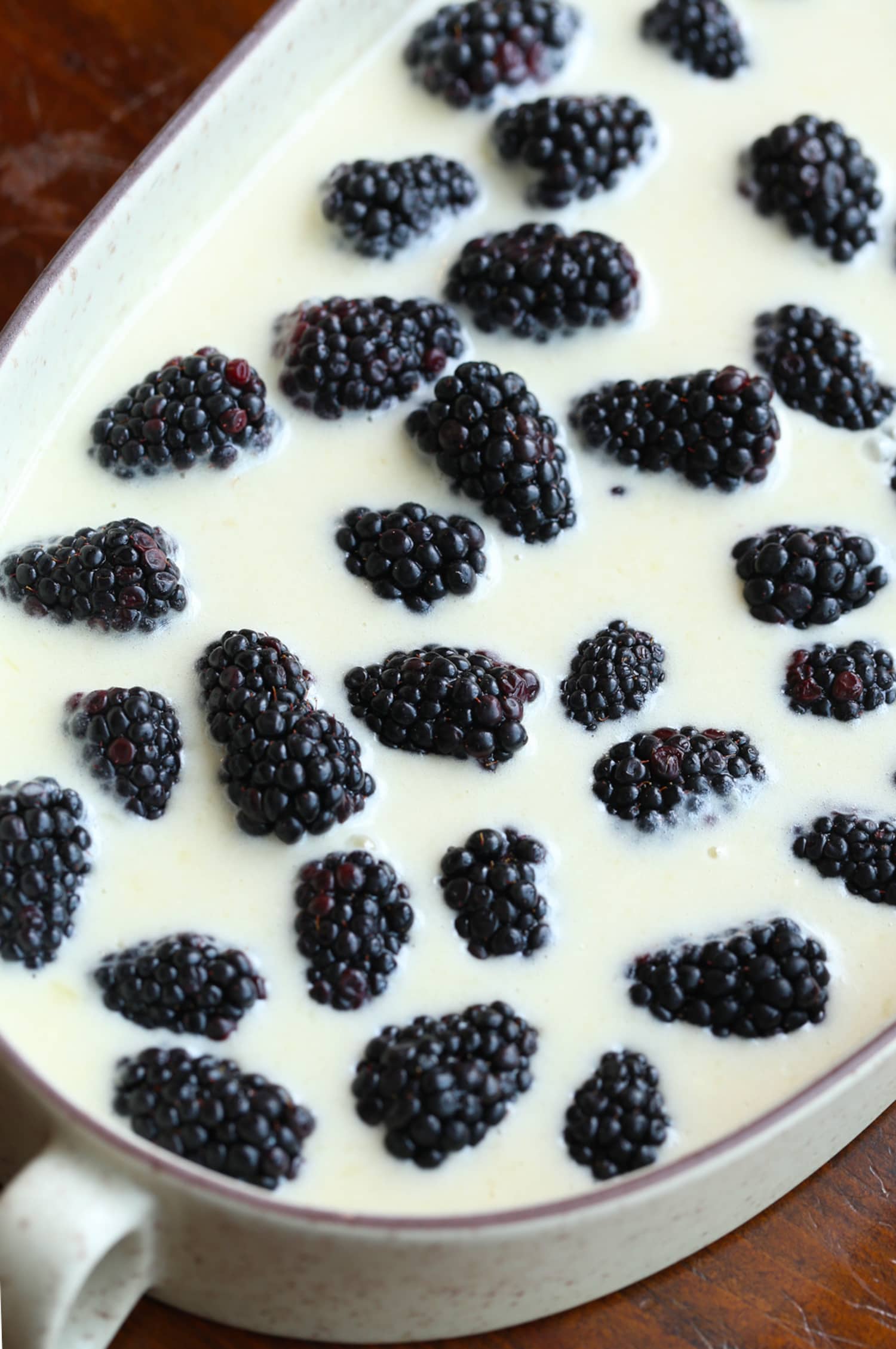 Placing a simple cobbler batter in a casserole baking dish with blackberries before placing in the oven