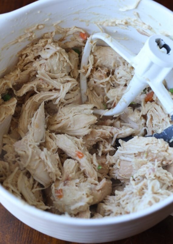 shredded chicken in a mixing bowl with the paddle attachment