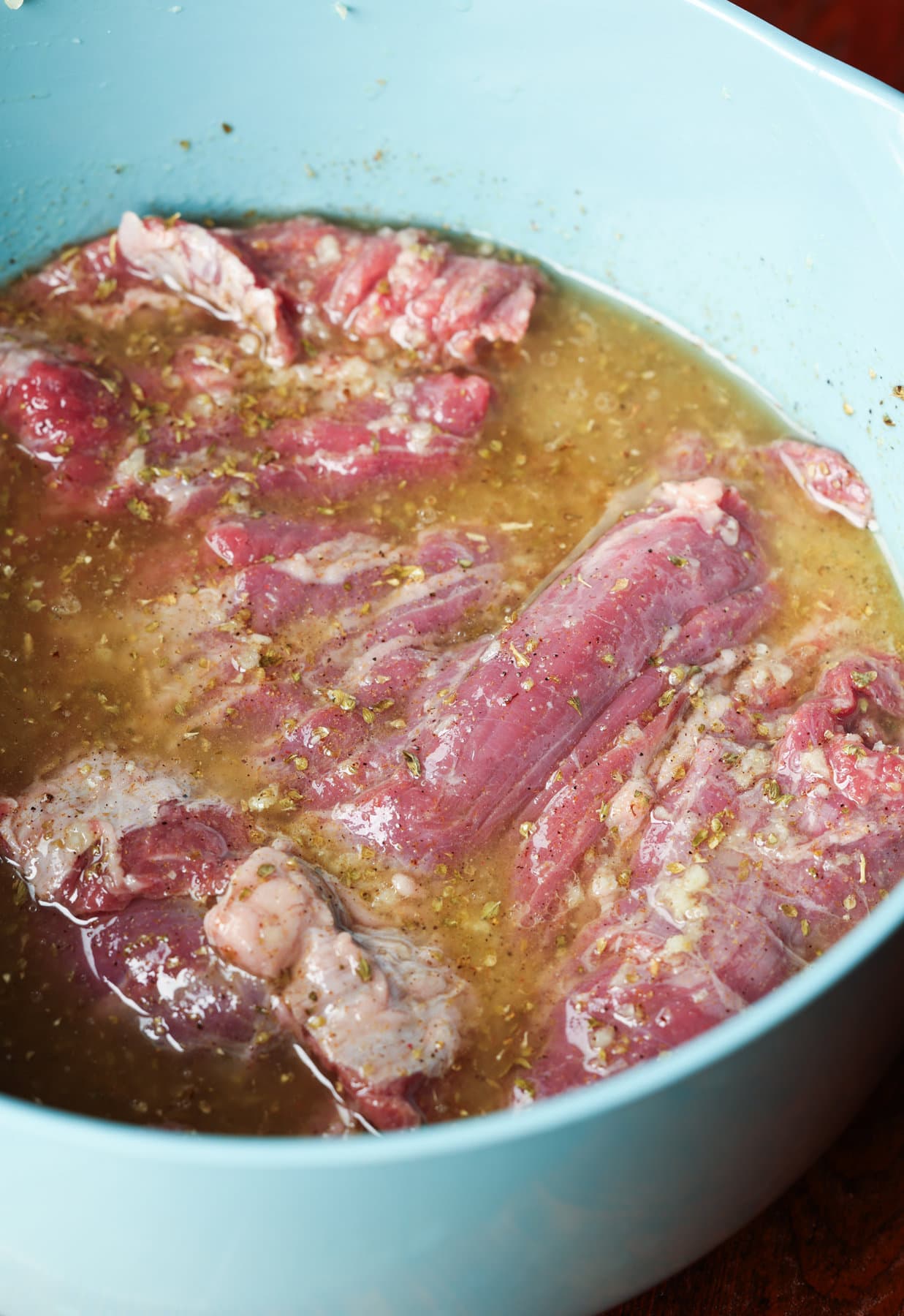 marinating skirt steak in a large blue bowl