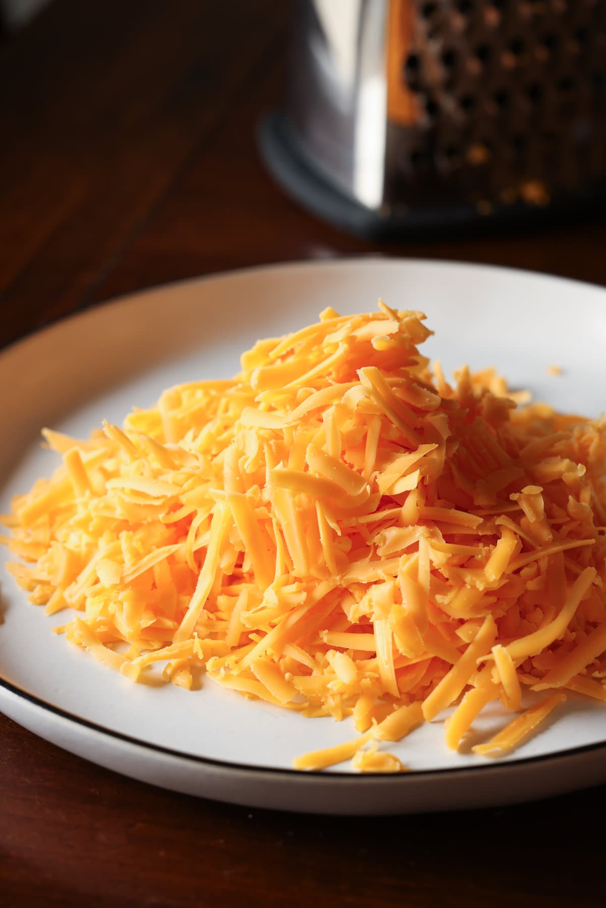 Grated cheddar cheese on a white plate