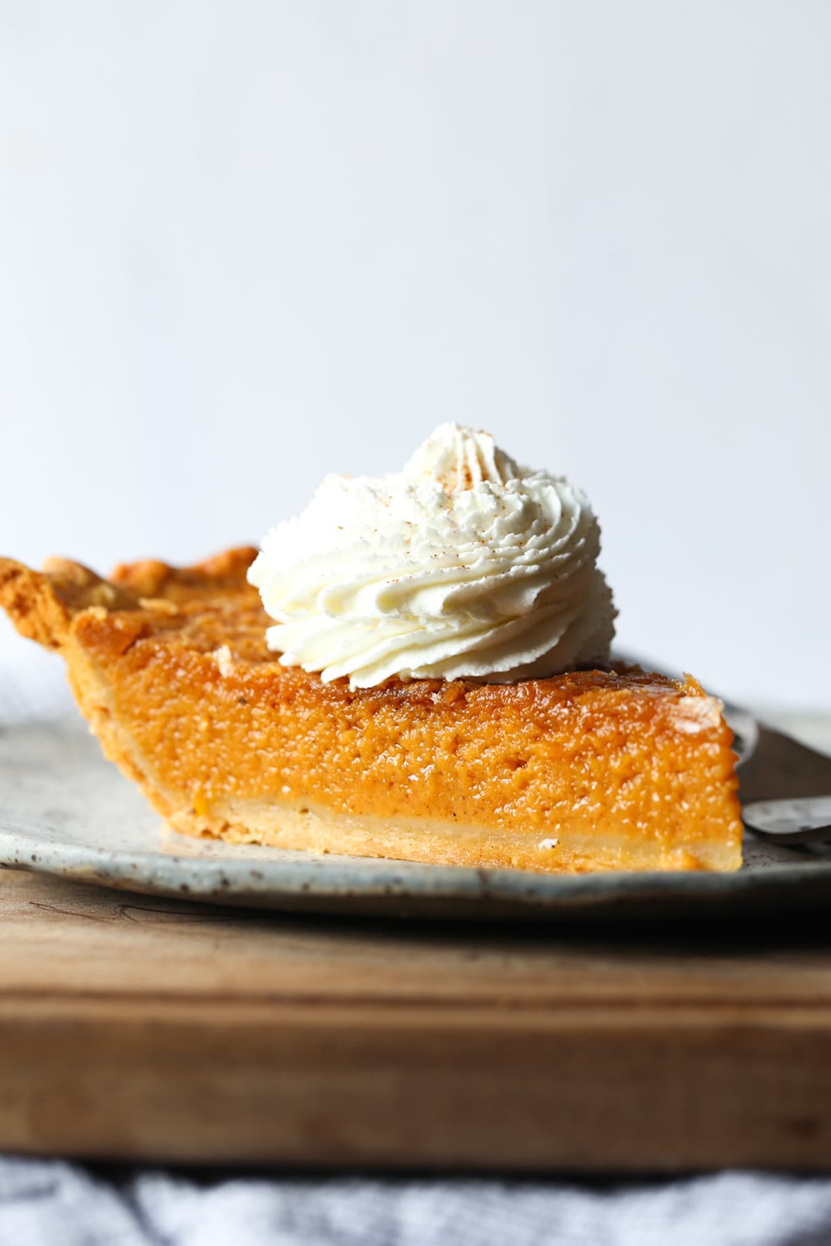 A slice of easy sweet potato pie topped with a dollop of whipped cream