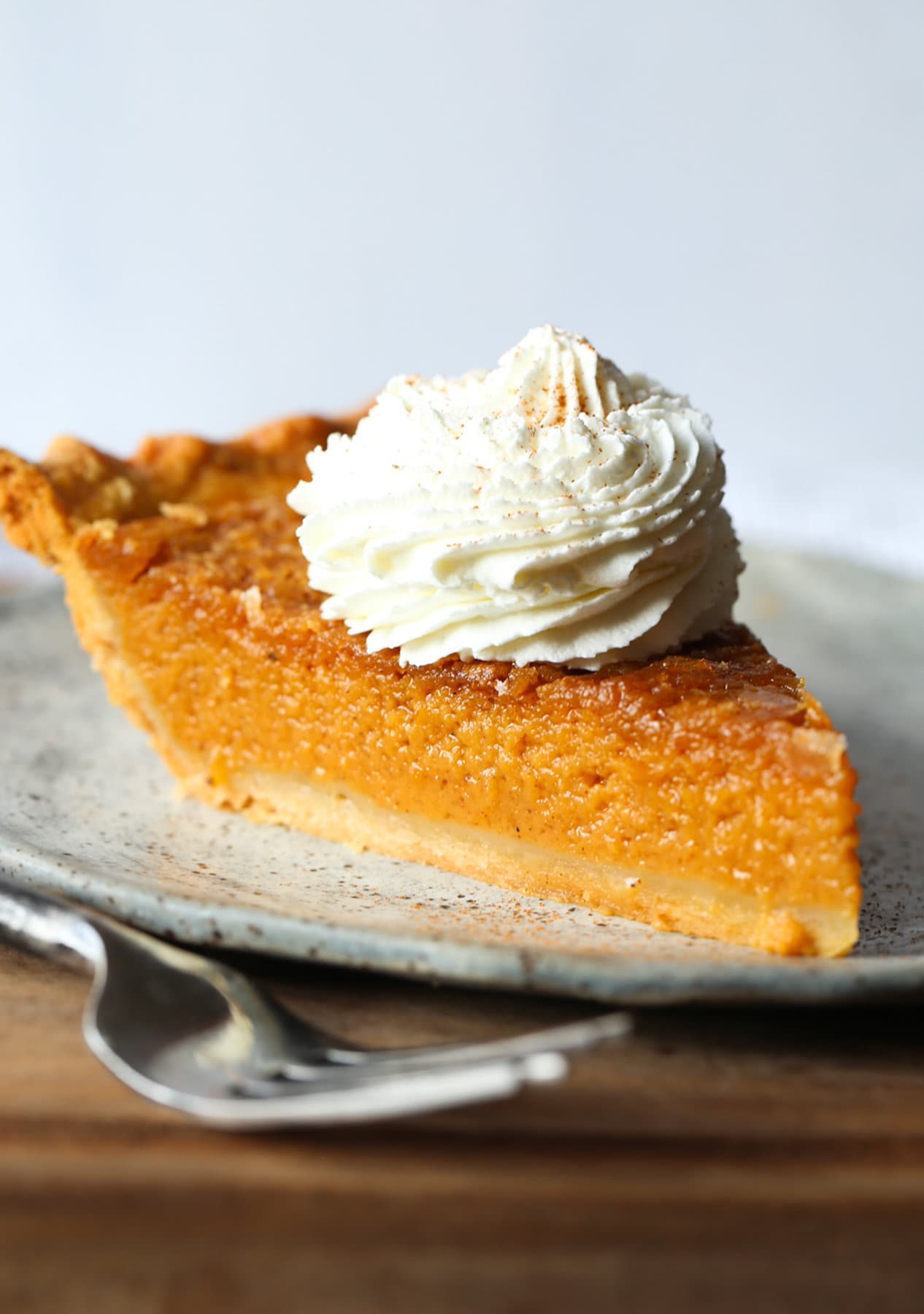 A slice of homemade sweet potato pie topped with whipped cream
