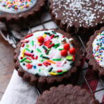 A Chocolate Sugar Cookie Topped with Icing and Christmas Themed Sprinkles