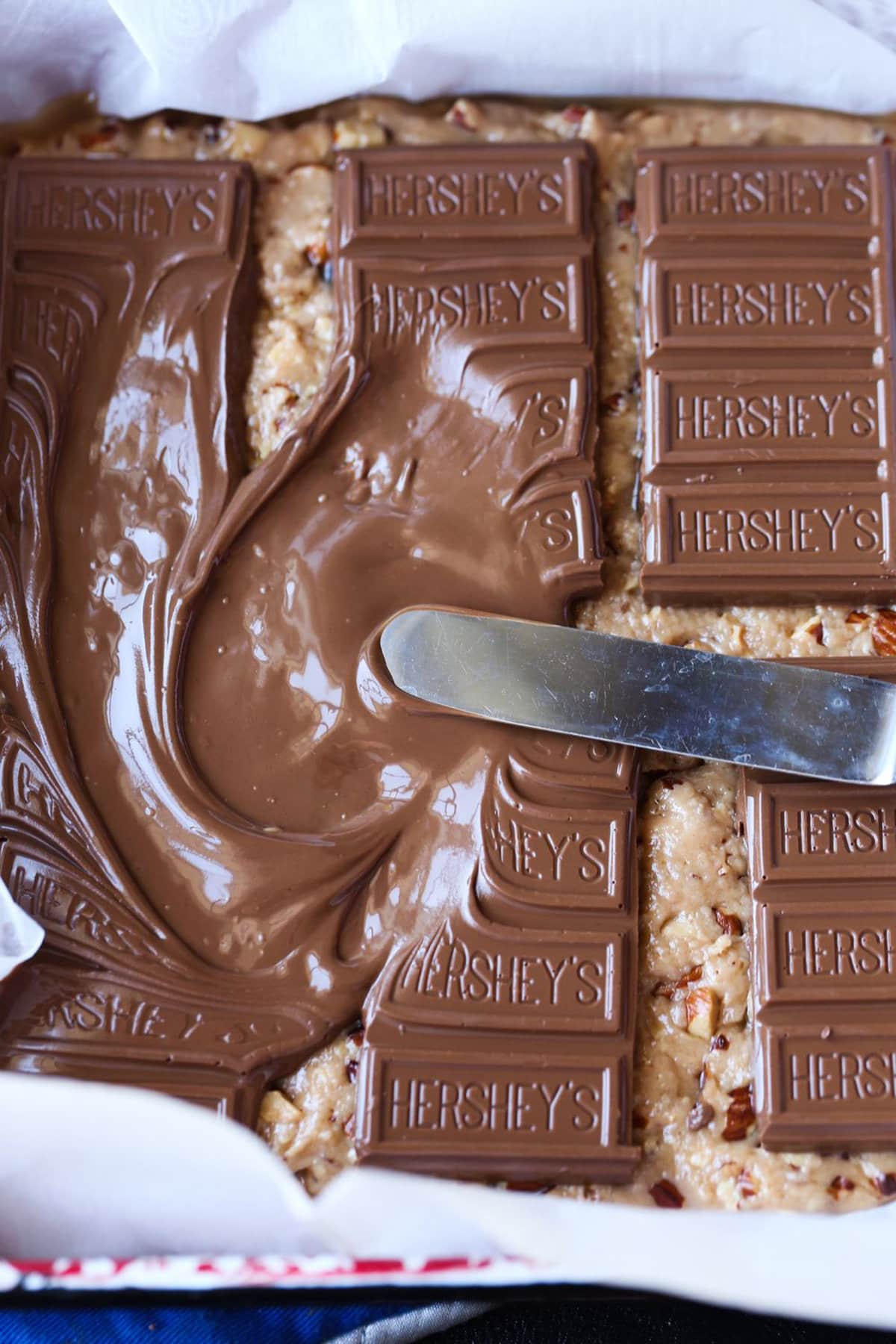 Melted Hershey's being spread on toffee mixture